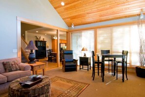 Relax in this stylish living area with a high ceiling, comfortable sofa, and dining table for two.