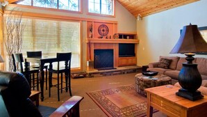 Un salon chaleureux avec une cheminée, un plafond en bois et de grandes fenêtres.
