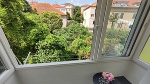 A balcony with a view of a residential area, a small table with a vase of flowers, and a tiled floor. - Orchidea Apartment Split in the center (Split)