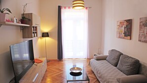 A modern living room with a flat-screen TV, a coffee table, a sofa, and artwork on the walls. - Orchidea Apartment Split in the center (Split)