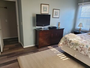 A bedroom with a bed, a dresser, a television, and framed pictures on the wall.