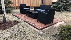 Eine Terrasse mit Gartenmöbeln, einem Holzzaun und einem Haus im Hintergrund.