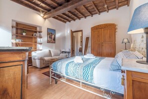 A bedroom with a bed, wooden wardrobe, and a desk with a lamp.