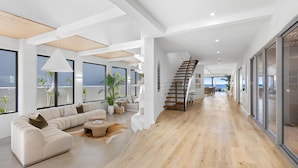 A modern interior with a wooden floor, a sofa, a coffee table, and a staircase. - Saltwater Beach House (Yaroomba)