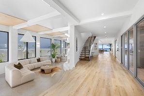 A modern interior with a wooden floor, a sofa, a coffee table, and a staircase.
