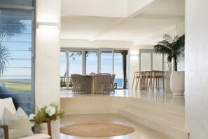 Amplia sala de estar con un ventanal que ofrece vistas panorámicas, un comedor con mobiliario de mimbre y una decoración de diseño moderno.