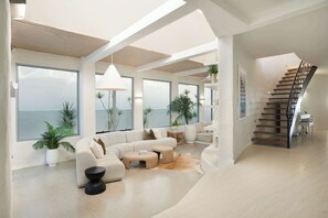 Un amplio salón con un sofá grande, una mesa de centro y una escalera.