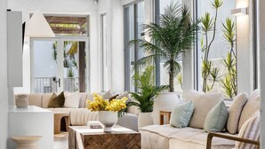 A modern living room with a sofa, coffee table, and potted plants. - Saltwater Beach House (Yaroomba)