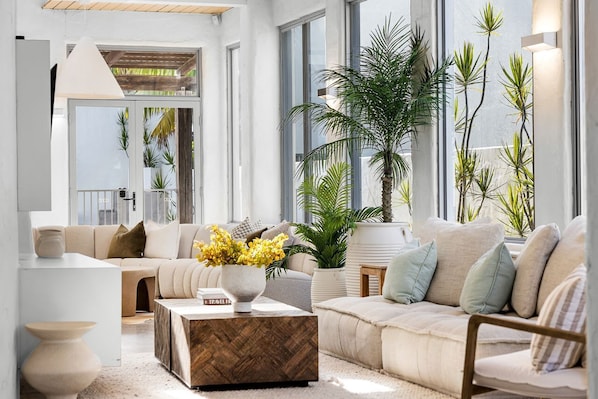A modern living room with a sofa, coffee table, and potted plants.