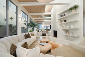 Una sala de estar moderna con un sofá modular grande, una chimenea y estanterías empotradas con libros y adornos.