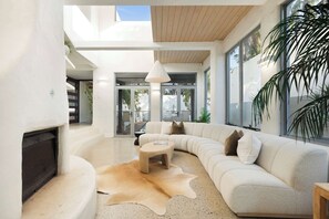Una sala de estar moderna con un sofá blanco curvo, una mesita redonda y una alfombra de cuero.
