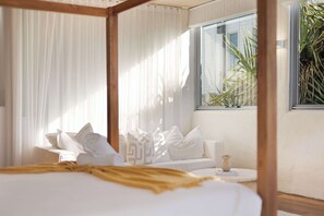 Une chambre à coucher avec un lit à baldaquin, un canapé, une petite table et une fenêtre donnant sur un paysage verdoyant.