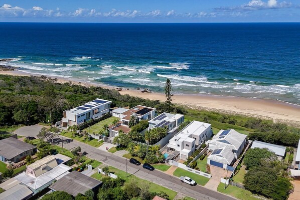 Un quartier résidentiel en bord de mer, avec des maisons modernes, une plage et une vue dégagée sur l’océan.