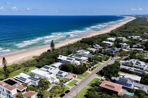 Un quartier résidentiel en bord de mer où les maisons sont équipées de panneaux solaires, et qui offre un accès à une plage ainsi qu’une vue dégagée sur l’océan.