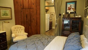 A bedroom with a bed, a chair, a dresser, a wardrobe, and a cabinet.