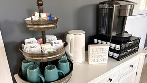 A coffee station with a tray of TAZO tea bags, a coffee maker, and a sign that reads "COFFEE AND FRIENDS A PERFECT BLEND".