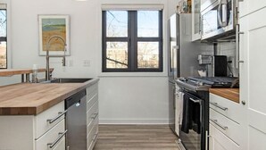 Una cocina moderna con encimera de madera, electrodomésticos de acero inoxidable y ventana con vistas al exterior.