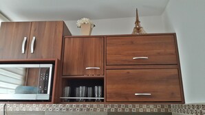 A kitchen with wooden cabinets, a built-in microwave, and a decorative Eiffel Tower model. - Charming little house in Tlaquepaque (San Juan)