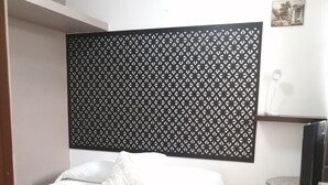 A bedroom with a bed, a black decorative panel, a small table, and a chair. - Charming little house in Tlaquepaque (San Juan)