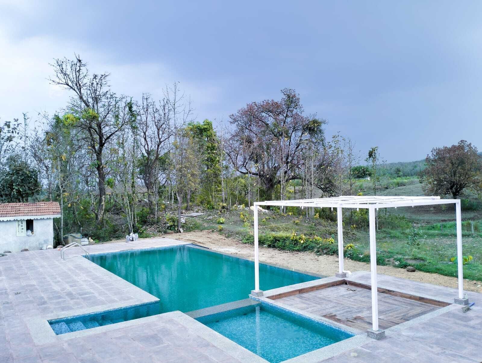 A rectangular swimming pool with a white pergola structure in the background.