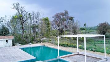 Una piscina rectangular con una estructura de pérgola blanca al fondo.