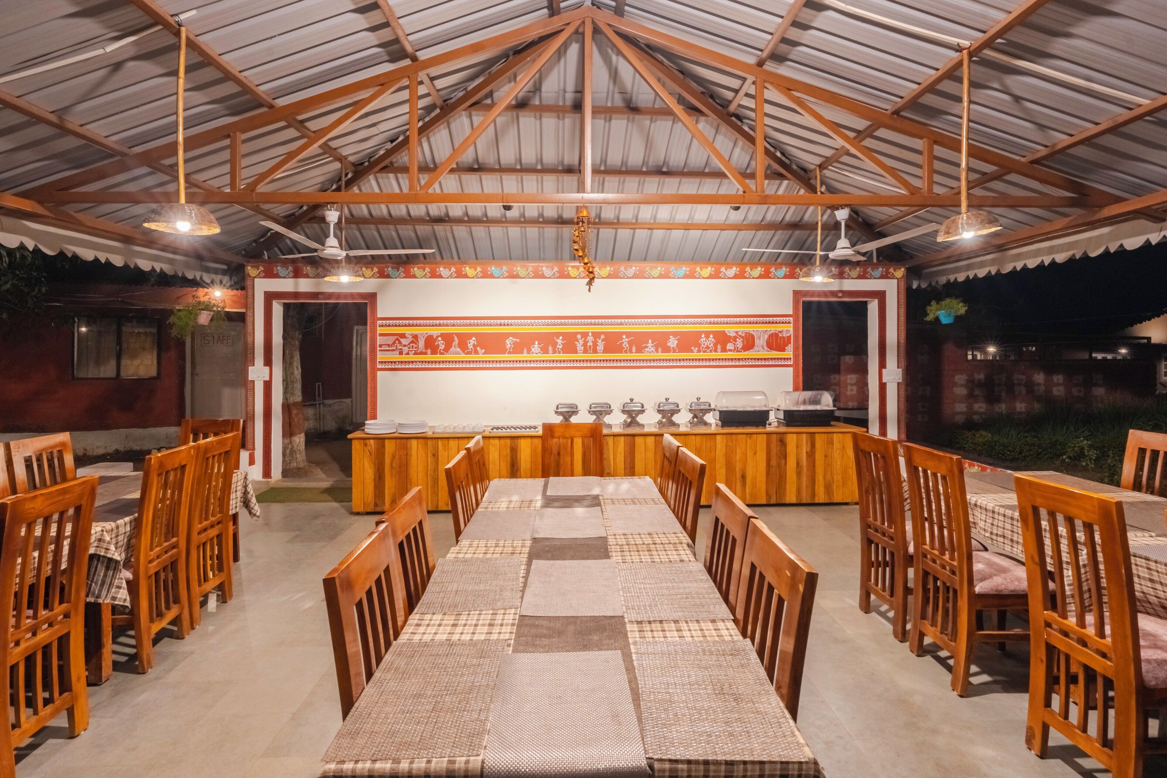 Comedor con una larga mesa, sillas de madera y un techo con vigas metálicas.
