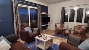 A living room with a brown sofa, two armchairs, a small table with a remote control, and a TV on a stand. - Villa Tomito, Arco da Calheta (Arco da Calheta)