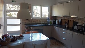 A modern kitchen with a dining table, chairs, a sink, and various appliances. - Villa Tomito, Arco da Calheta (Arco da Calheta)