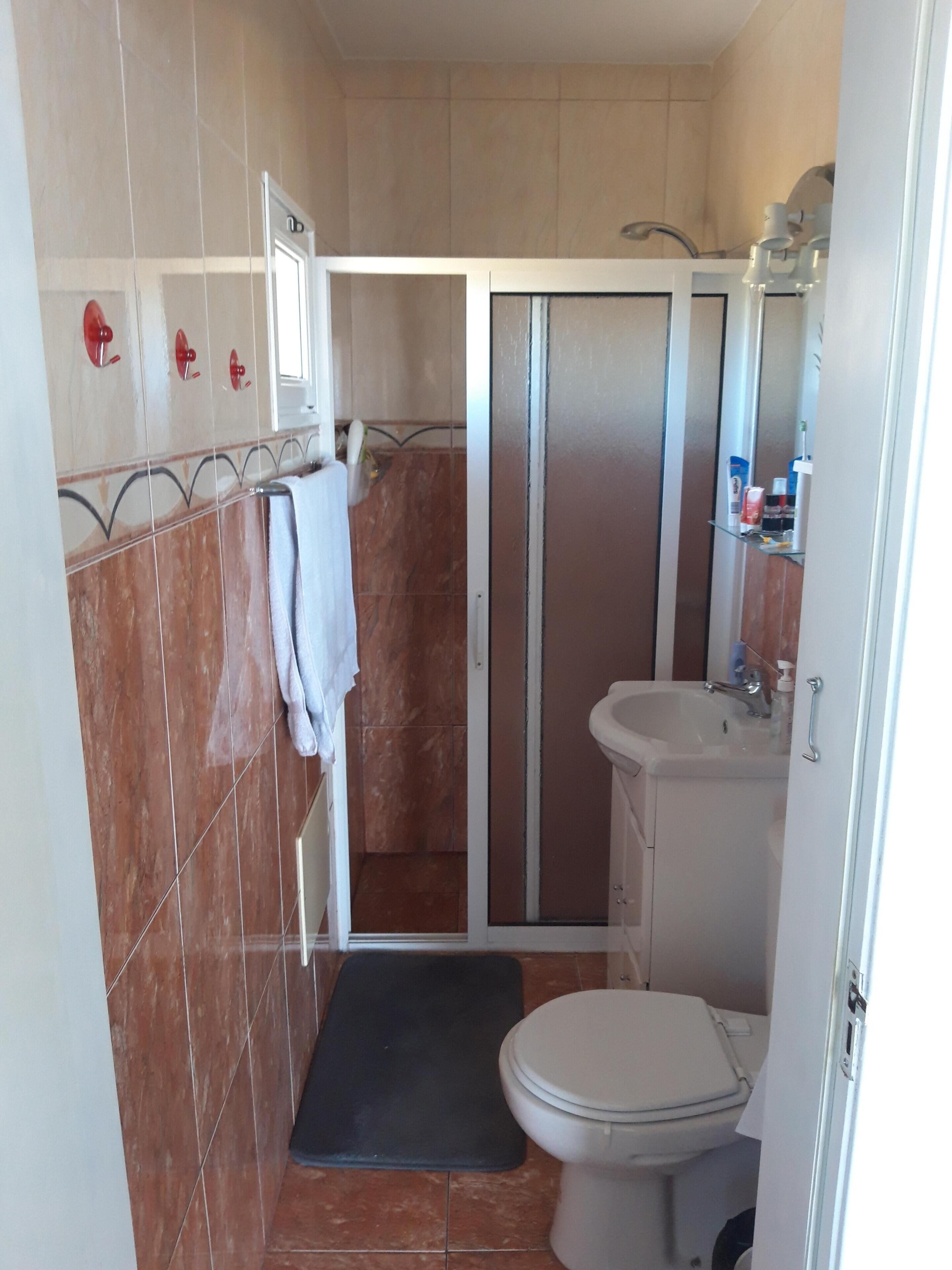 Un baño pequeño con cabina de ducha, inodoro y lavabo.