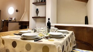 A dining area with a table set for four, featuring a polka dot tablecloth, plates, glasses, cutlery, and a bottle of wine. - Top Ferienwohnung - Ticino Lugano (Comano) (Comano)
