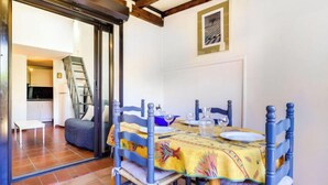 A dining area with a table set for four, blue chairs, and a yellow tablecloth. - Les Amandines by Interhome (Gruissan)