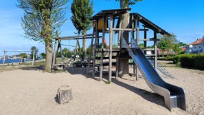 Ein Spielplatz mit Rutsche, Schaukeln und Klettergerüsten.