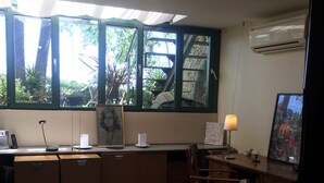 Une chambre à coucher comprenant un lit, un bureau, une chaise, une petite table et une fenêtre donnant sur des arbres et un escalier.