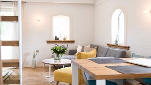 Un salon moderne avec une table en bois, un canapé et une petite table ronde sur laquelle est posé un vase de fleurs.