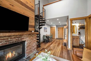 A modern interior with a fireplace, a dining area, and a kitchen. - SnowPine Condo, Sleeps 8, Patio, A/C (Great Valley)