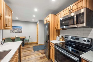 Une cuisine moderne avec des meubles en bois, des appareils électroménagers en acier inoxydable et un coin repas comprenant une table et des chaises.