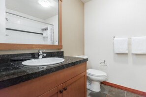A bathroom with a sink, mirror, toilet, and towels.