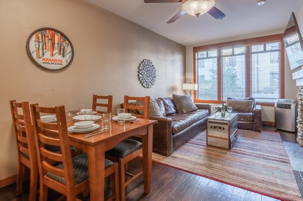 Un coin repas avec une table en bois dressée pour quatre personnes, un canapé en cuir et un élément décoratif mural.