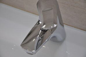 A chrome faucet with a modern design, mounted on a white sink.