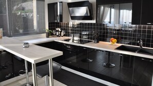 A modern kitchen with black cabinets, a white countertop, and stainless steel appliances. - SKYLINE Penthouse Apartment Cap-D'ail, Monaco (Cap-d'Ail)