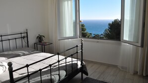 A bedroom with a bed, a small bedside table with a plant, and a window with a view of the sea. - SKYLINE Penthouse Apartment Cap-D'ail, Monaco (Cap-d'Ail)