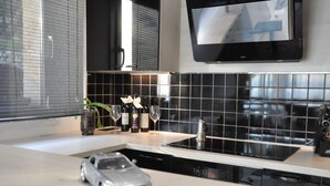A modern kitchen with a black tiled backsplash, a built-in oven, and a small car model on the counter.