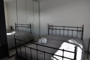 A bedroom with a bed, a wardrobe, and a mirror.
