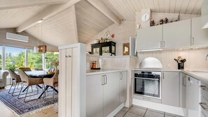 Ett modernt kök med vita skåp, en inbyggd ugn och en matplats med bord och stolar.