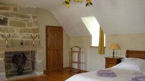 A bedroom with a stone fireplace, wooden bed, and a skylight. - The Closerie du Manoir for 7 people (Audierne)