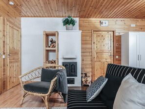 Un interior de madera con un sofá, una silla de mimbre, una chimenea y puertas de madera.