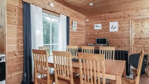 A wooden cabin with a dining area, a television, and a window with curtains. - Vacation home B by Interhome (Porvoo)