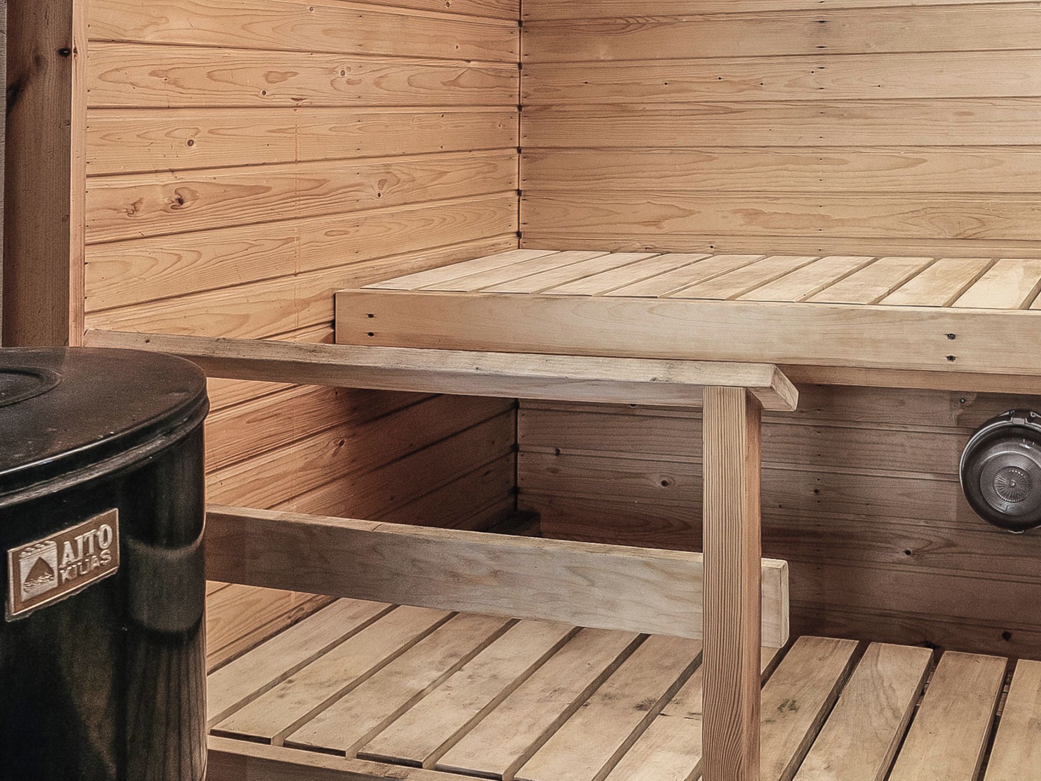 A sauna with a wooden bench and a trash bin.