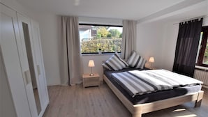 A bedroom with a bed, bedside lamps, a window, and a wardrobe. - Vacation apartment T & T 3 (Malente)