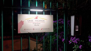 A sign for 'CASE VACANZA' hotel with contact information and a silhouette of a cat.